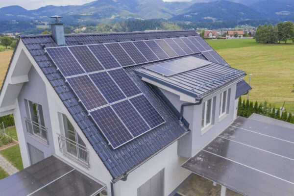 Žalia energija ar pelnas kišenėje? Patarimai, kaip nepermokėti už saulės elektrinę Saulės elektrinė ant gyvenamojo namo stogo saulėtą dieną, rodanti švarios energijos gamybą.